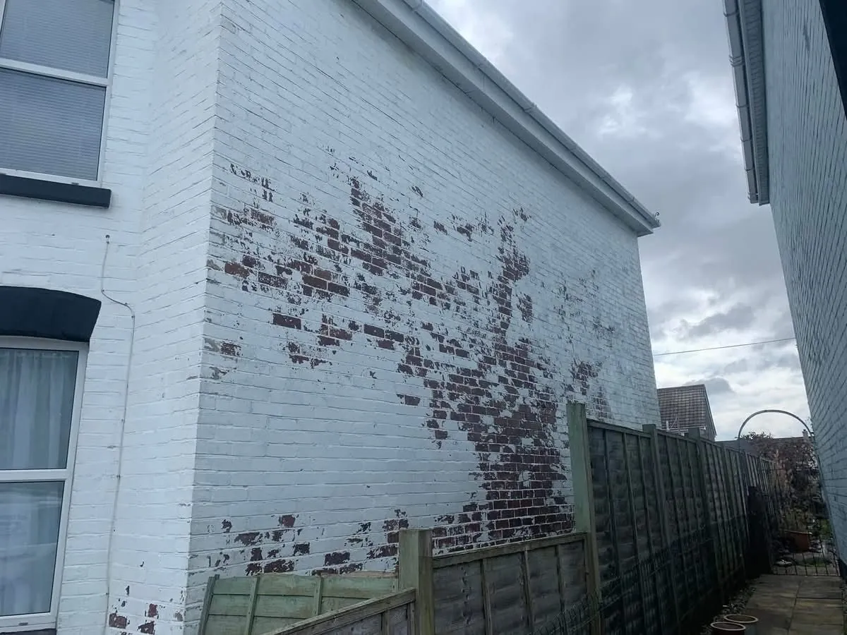 Peeling paint on a brick wall before redecoration in Looe